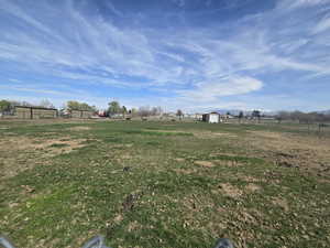 View of yard with an outdoor structure, fence, a storage unit, and a rural view