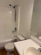 Full bathroom featuring toilet, vanity, bathtub / shower combination, and wood finished floors
