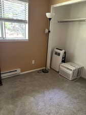 Unfurnished bedroom with a baseboard heating unit, multiple windows, and carpet