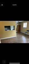 Unfurnished living room with wood-type flooring, a baseboard heating unit, and ceiling fan