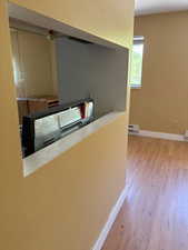 Corridor with wood finished floors, baseboard heating, and baseboards