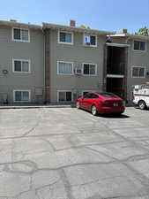 View of building exterior featuring uncovered parking and cooling unit
