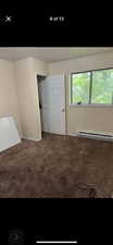 Unfurnished bedroom with carpet, a closet, and baseboard heating