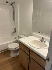 Bathroom featuring vanity, wood finished floors, toilet, and bathtub / shower combination