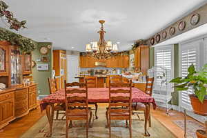 Dining space with a notable chandelier, sink, a textured ceiling, and light wood-type flooring