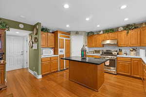 Kitchen with a kitchen island, stainless steel gas range, backsplash, and light hardwood / wood-style flooring