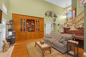 Living room featuring a notable chandelier, light wood-type flooring, and a high ceiling