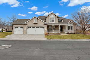 View of front of house featuring a porch, a garage, and a front lawn