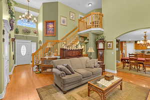 Living room featuring a towering ceiling, wood-type flooring, and a notable chandelier