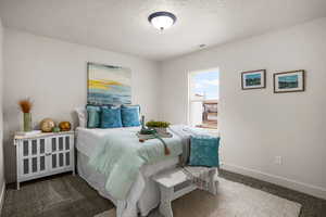 Bedroom featuring a textured ceiling and dark colored carpet