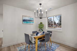 Dining space with a textured ceiling, light hardwood / wood-style floors, and a chandelier