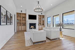 Living room with an inviting chandelier, light hardwood / wood-style floors, and built in shelves