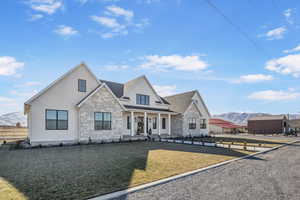 View of front of home with a porch, a mountain view, and a front yard