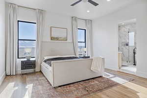 Bedroom featuring ceiling fan, connected bathroom, and multiple windows