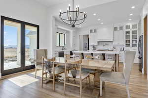 Dining area featuring an inviting chandelier, sink, light hardwood / wood-style flooring, and french doors