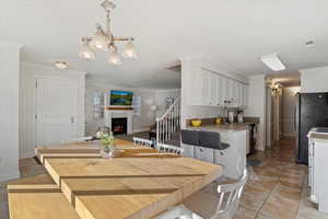 Dining space featuring an inviting chandelier, crown molding, sink, and light tile patterned floors