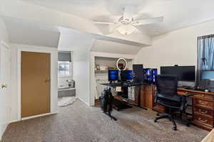 Carpeted office space featuring lofted ceiling and ceiling fan