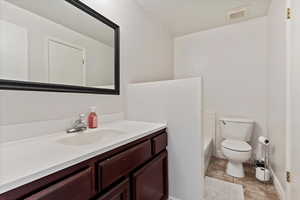 Bathroom with vanity, a bath, and toilet