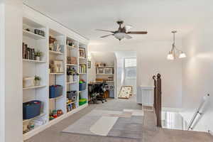 Rec room with light colored carpet and ceiling fan with notable chandelier