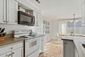 Kitchen featuring pendant lighting, white cabinetry, ornamental molding, light tile patterned flooring, and white electric stove