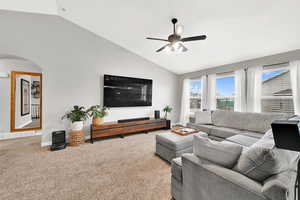 Carpeted living room featuring vaulted ceiling and ceiling fan