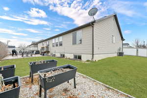 Rear view of property featuring cooling unit, a lawn, and a patio area