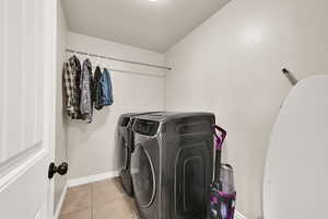 Laundry area with washing machine and dryer and light tile patterned floors