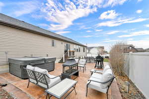 View of patio featuring grilling area, an outdoor hangout area, and a hot tub