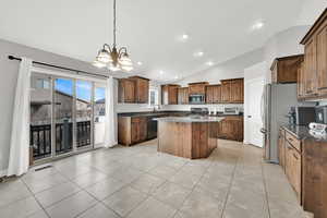 Kitchen featuring lofted ceiling, hanging light fixtures, a center island, light tile patterned floors, and stainless steel appliances