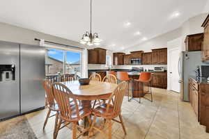 Dining room featuring an inviting chandelier, sink, vaulted ceiling, and light tile patterned flooring