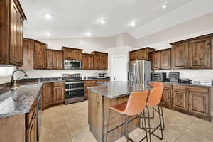 Kitchen with light tile patterned flooring, stainless steel appliances, a center island, and sink