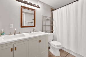 Full bathroom featuring shower / bathtub combination with curtain, vanity, toilet, and tile patterned flooring