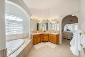 Primary Bathroom with tile patterned flooring, vanity, and tiled tub