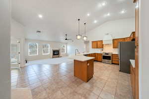 Open concept Kitchen featuring premium range hood, appliances with stainless steel finishes, pendant lights, light tile patterned flooring.