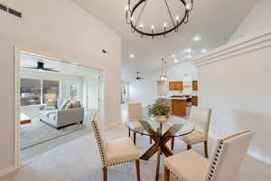 Carpeted dining room with high vaulted ceiling, sink, and ceiling fan