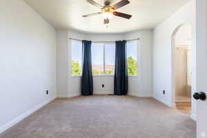 Carpeted empty room featuring ceiling fan