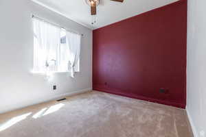 Carpeted empty room featuring ceiling fan