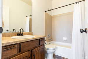 Full bathroom with vanity, shower / tub combo, and toilet