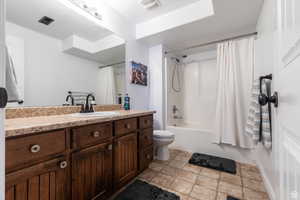 Full bathroom featuring toilet, vanity, and shower / bathtub combination with curtain