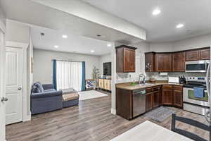 Kitchen with sink, dark brown cabinets, stainless steel appliances, and light wood-type flooring