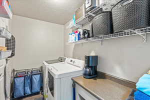 Laundry area with separate washer and dryer and a textured ceiling