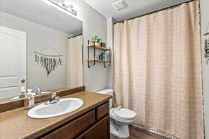 Bathroom featuring wood-type flooring, vanity, a textured ceiling, and toilet