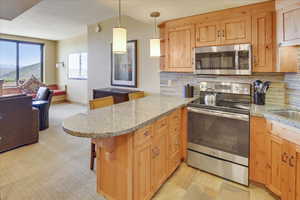 Kitchen featuring stainless steel appliances, kitchen peninsula, a breakfast bar area, and backsplash