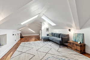 Additional living space with hardwood / wood-style floors and lofted ceiling with skylight