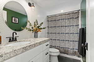 Bathroom with tasteful backsplash, vanity, tile patterned floors, toilet, and walk in shower