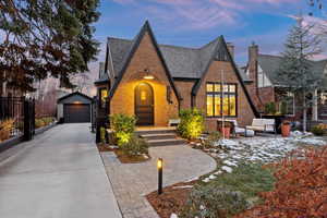 Tudor-style house with a garage, an outdoor structure, and an outdoor hangout area