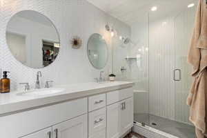 Bathroom featuring vanity, an enclosed shower, tile walls, and backsplash