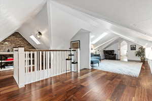 Bonus room with vaulted ceiling with skylight and hardwood / wood-style floors