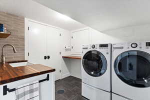 Washroom featuring sink, washing machine and dryer, and dark tile patterned floors