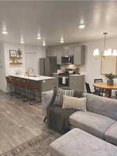 Living room with a chandelier, light hardwood / wood-style floors, sink, and a textured ceiling